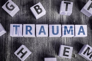 The word TRAUMA spelled out with Scrabble tiles